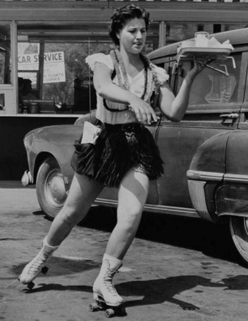 Female car hop roller skating-at 1950s drive in restaurant